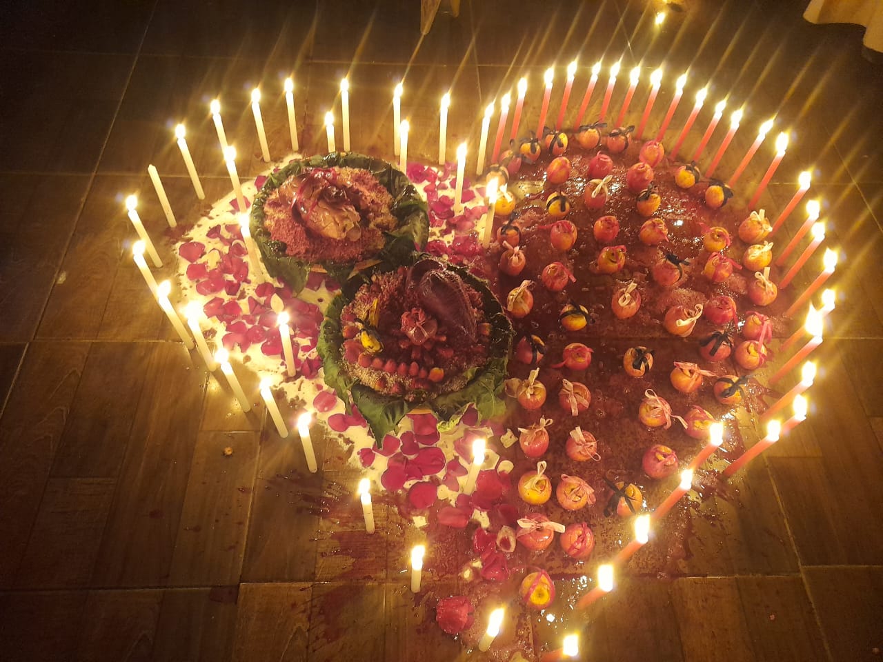 Oferenda ritual cercada por velas, com rosas vermelhas e composição simbólica.